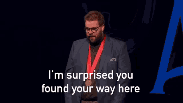 a man wearing glasses and a medal around his neck says i 'm surprised you found your way here