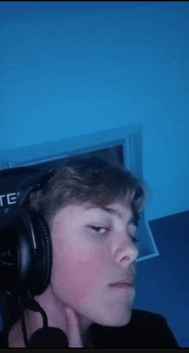 a young man wearing headphones and a microphone looks at the camera