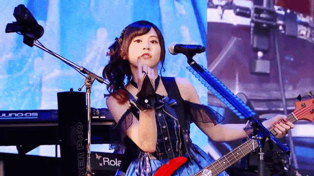 a woman sings into a microphone while holding a guitar in front of a keyboard that says super pro