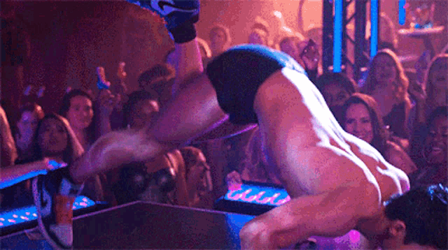 a man is doing a handstand in front of a crowd in a club .