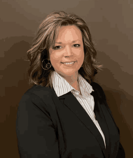 a woman wearing a black jacket and a white striped shirt smiles for the camera
