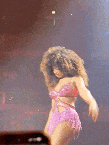 a woman in a pink outfit is dancing on stage