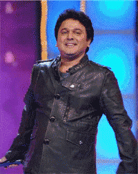 a man in a black leather jacket stands in front of a blue backdrop