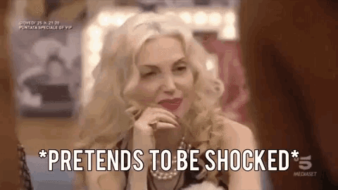 a woman is sitting in front of a mirror and saying pretends to be shocked