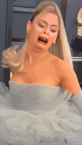 a woman in a white dress is making a funny face with her mouth open