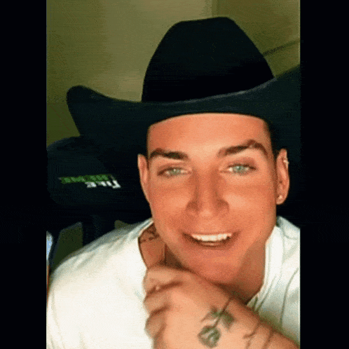 a young man wearing a black cowboy hat and a white shirt .