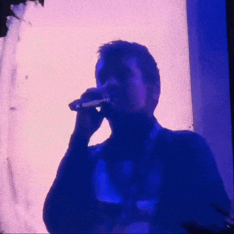 a man is singing into a microphone in front of a blue screen .