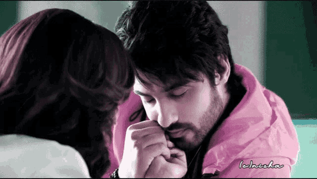 a man in a pink jacket holds a woman 's hand in front of his face