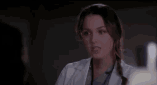 a close up of a woman in a lab coat and scrubs talking to a man .