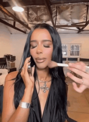 a woman with long black hair is getting her makeup done