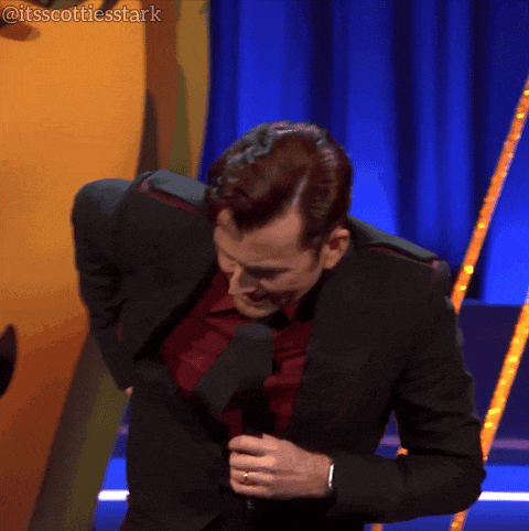 a man in a suit and tie is holding a microphone in front of a blue curtain that says itsscottiesstark on it