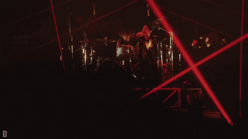 a man stands on a stage in front of a drum set with the letter d visible