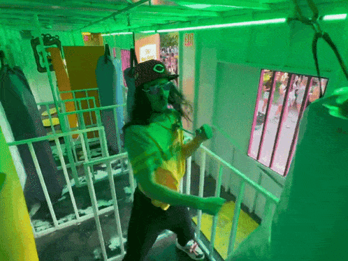 a person wearing a hat with the letter o on it stands in front of a green exit sign