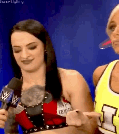 a woman is holding a microphone and talking into it while another woman watches .