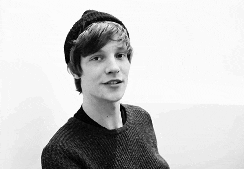 a black and white photo of a young man wearing a beanie