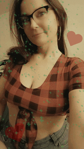 a woman wearing glasses and a plaid crop top takes a selfie