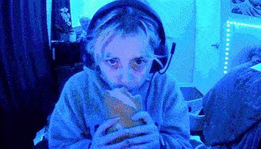 a girl wearing headphones is eating a sandwich in front of a blue background .