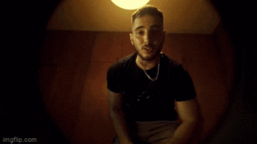a man in a black shirt is dancing in a dark room under a light ..