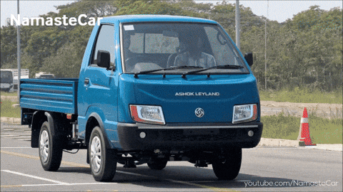 a blue aishok leyland truck is driving down a street
