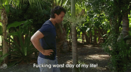 a man in a blue shirt is standing in the woods with his hands on his hips and says fucking worst day of my life