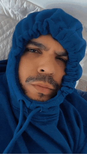 a man wearing a blue hoodie looks tired