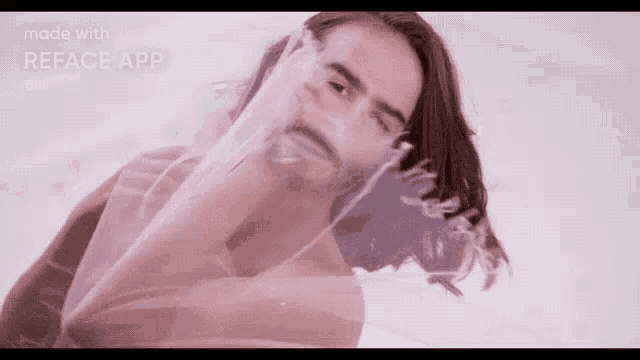 a man with long hair and a beard is making a funny face with his hand .