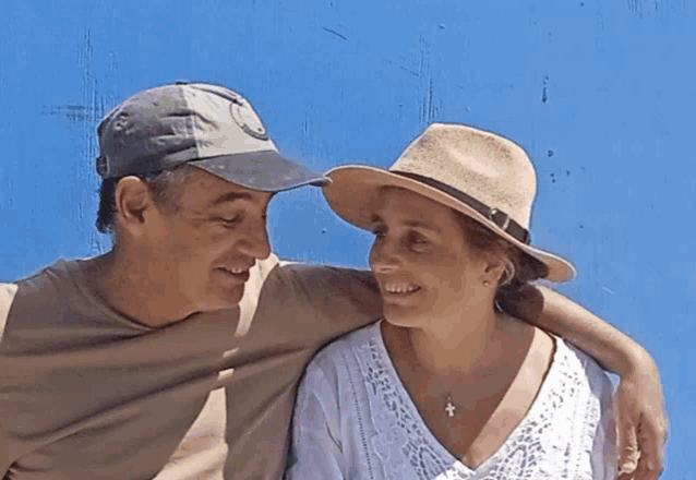 a man wearing a hat and a woman wearing a hat are smiling for the camera
