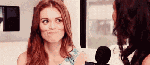 a woman with red hair is making a funny face while talking to another woman in front of a microphone .