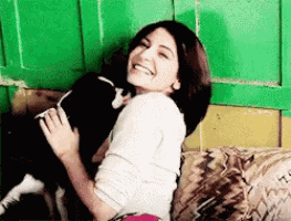 a woman is sitting on a couch holding a small dog .