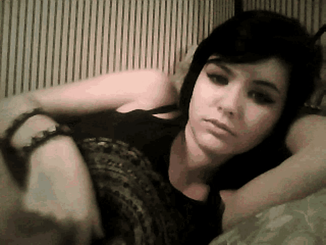 a woman laying on a bed with her head on her arm