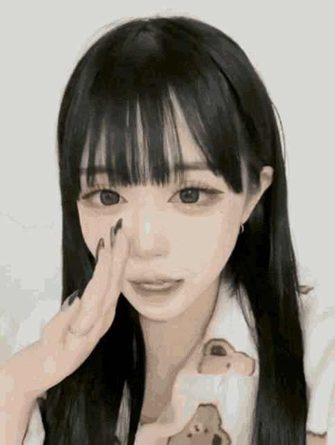 a girl with long black hair is wearing a white shirt with a bear on it