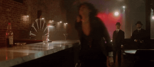 a woman is laying on a bar in a dark room with a red light shining on her face .