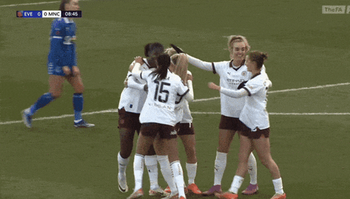 a group of female soccer players are hugging each other on a field and one of them has the number 15 on her back
