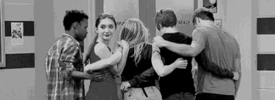 a group of people are hugging each other in a room .