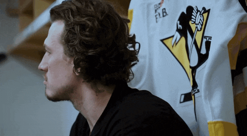 a man in a pittsburgh penguins jersey looks down