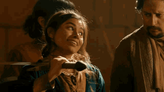 a young girl is holding a sword and smiling in front of a man