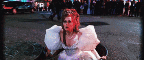 a woman in a wedding dress is sitting in a manhole cover