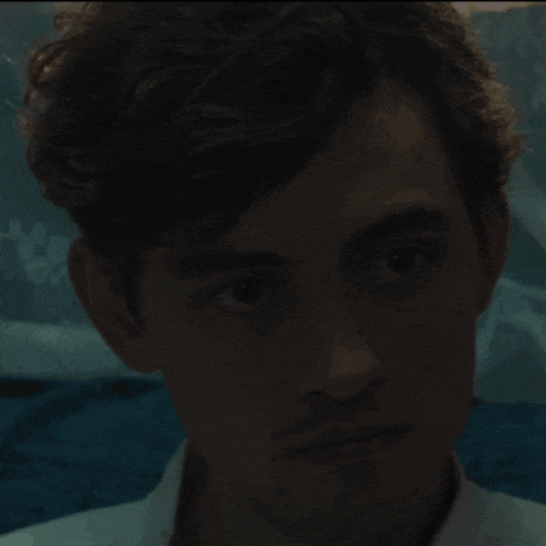 a close up of a young man 's face in a dark room