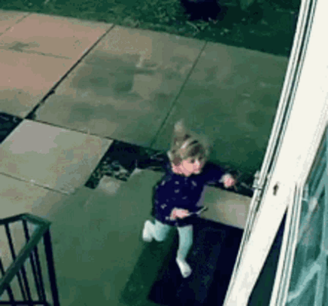 a little girl is running down the stairs of a building .
