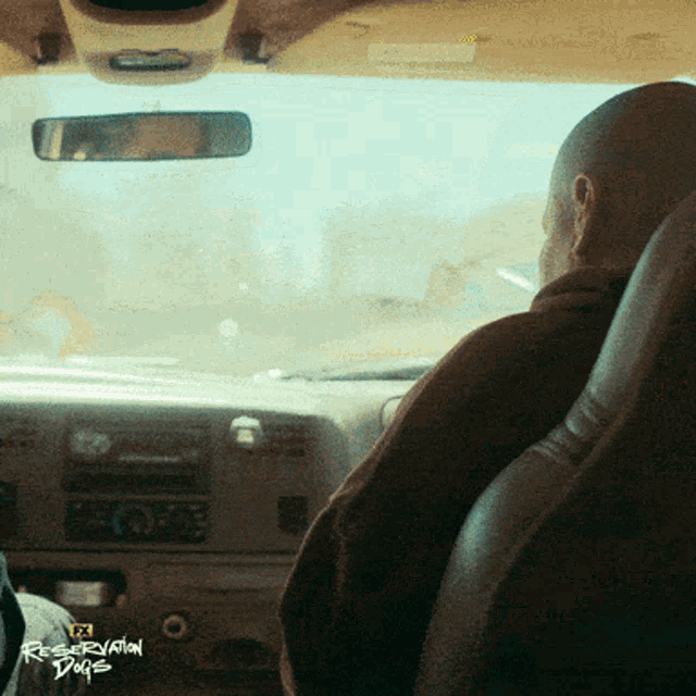 a man is driving a car with the words reservation dogs on the bottom