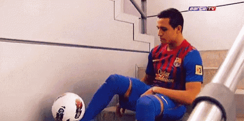 a man in a qatar foundation jersey is sitting on a staircase with a soccer ball ..