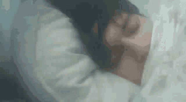 a person is laying in bed with their head on a pillow