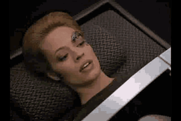 a woman is laying in a coffin with a robot on her head .