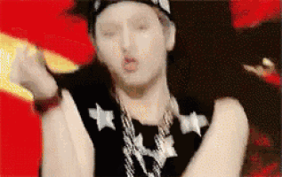 a man wearing a hat and a necklace is making a face