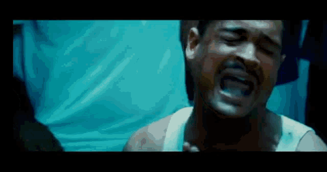 a man with a beard is crying with his mouth open in a dark room .
