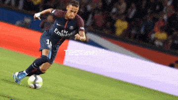a soccer player wearing a fly emirates jersey kicks a soccer ball