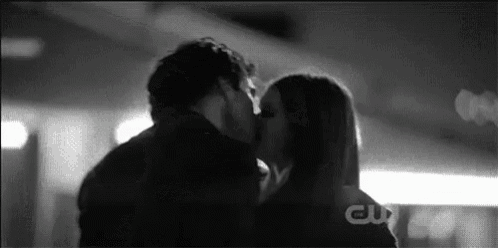 a man and a woman are kissing in a parking garage .