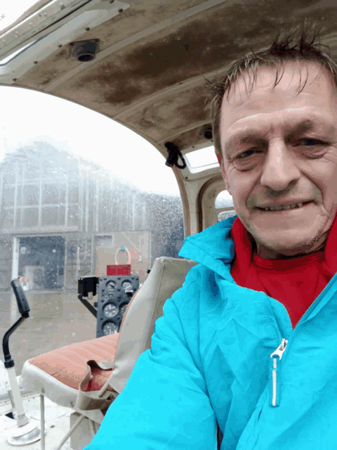 a man in a blue jacket is sitting in a helicopter cockpit