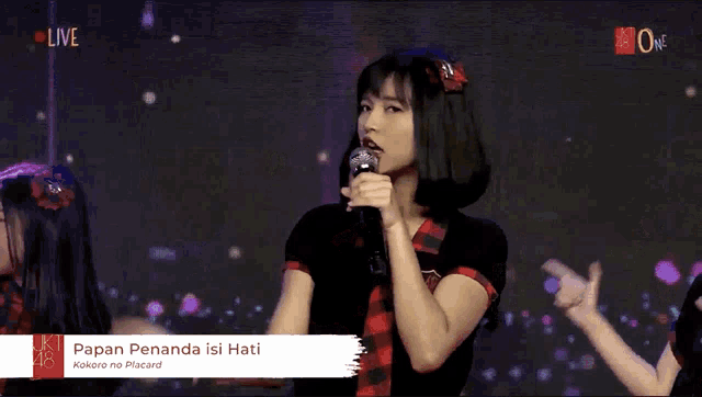 a girl singing into a microphone with papan penanda isi hati written on the screen