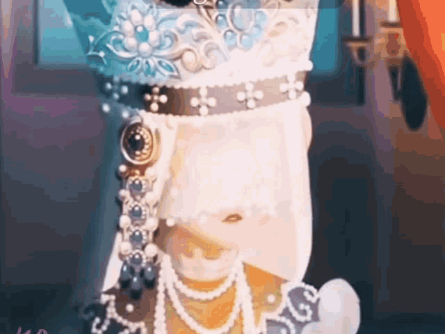 a doll is wearing a veil and pearls and a crown .